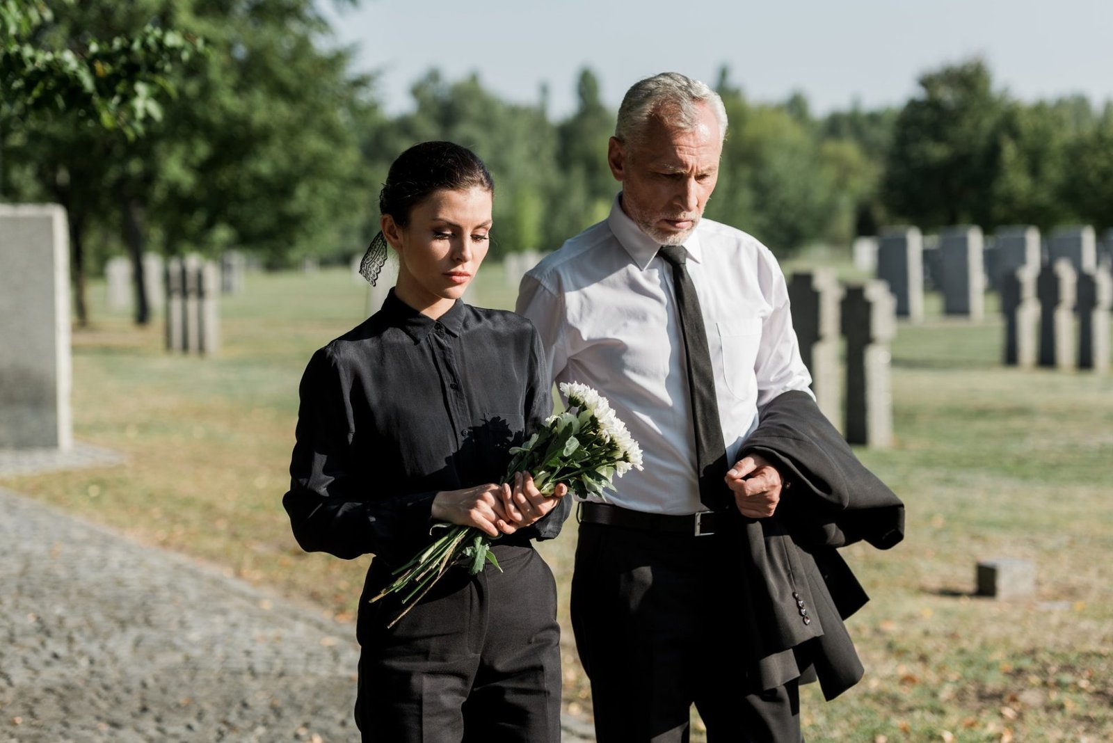 bearded senior man walking near woman with flowers on funeral.jpg