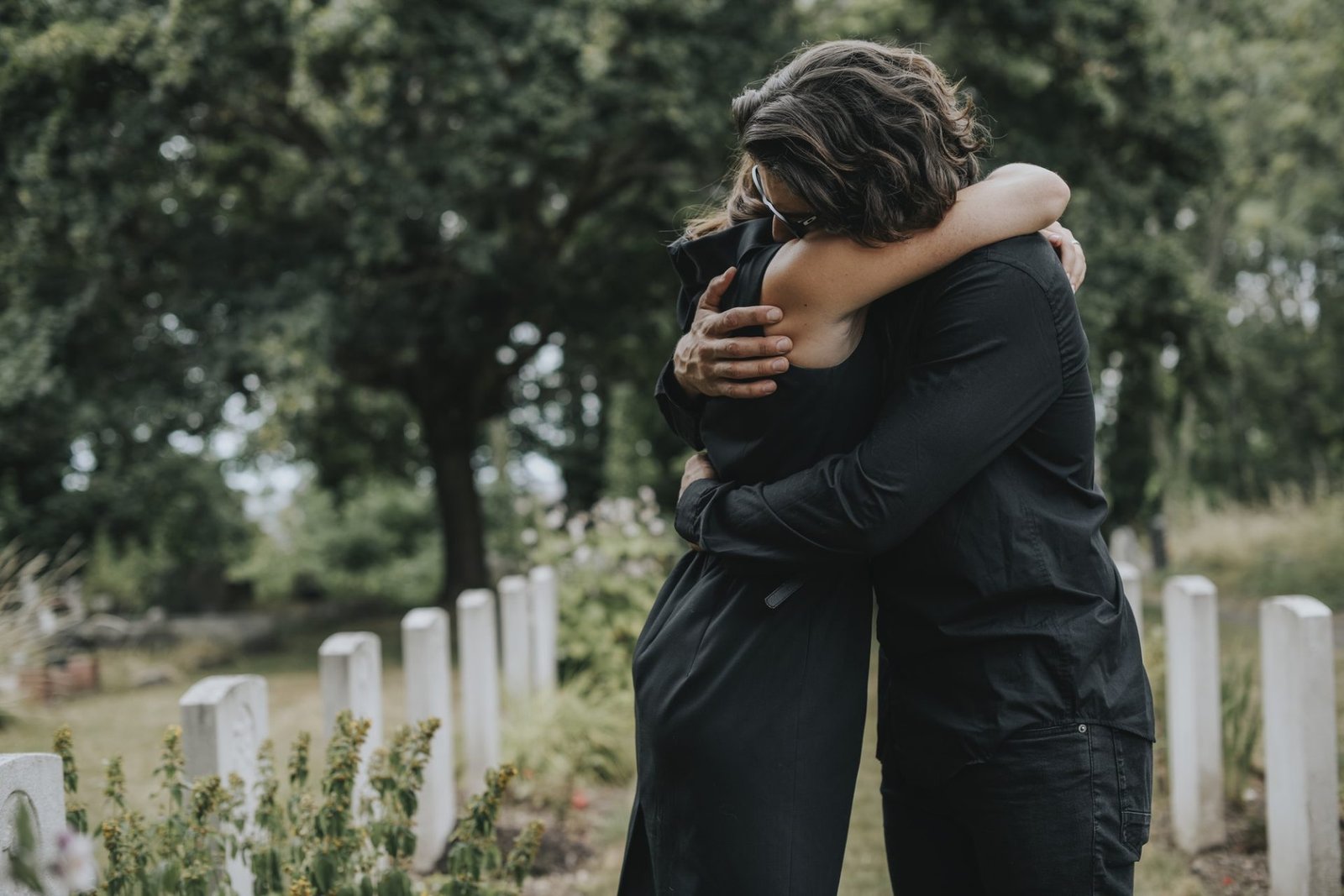 husband trying to comfort his wife at a graveyard.jpg