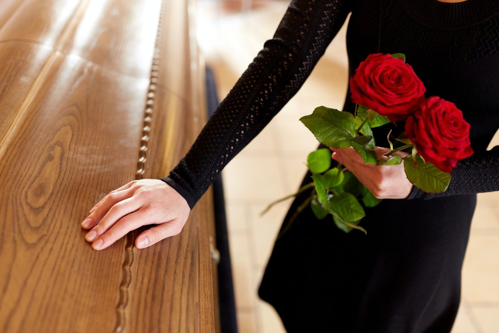 woman with red roses and coffin at funeral 1.jpg