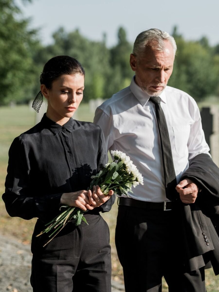 bearded senior man walking near woman with flowers on funeral.jpg