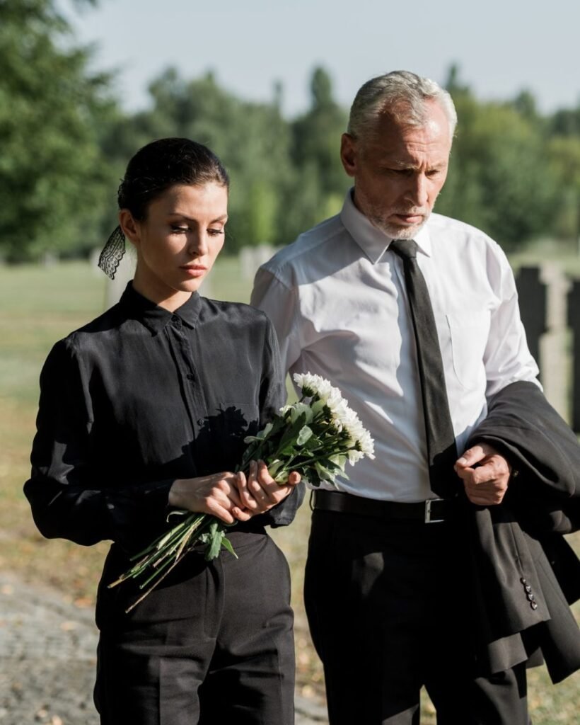 bearded senior man walking near woman with flowers on funeral e1636904705190.jpg