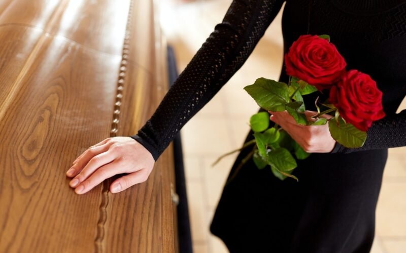 woman with red roses and coffin at funeral 1.jpg